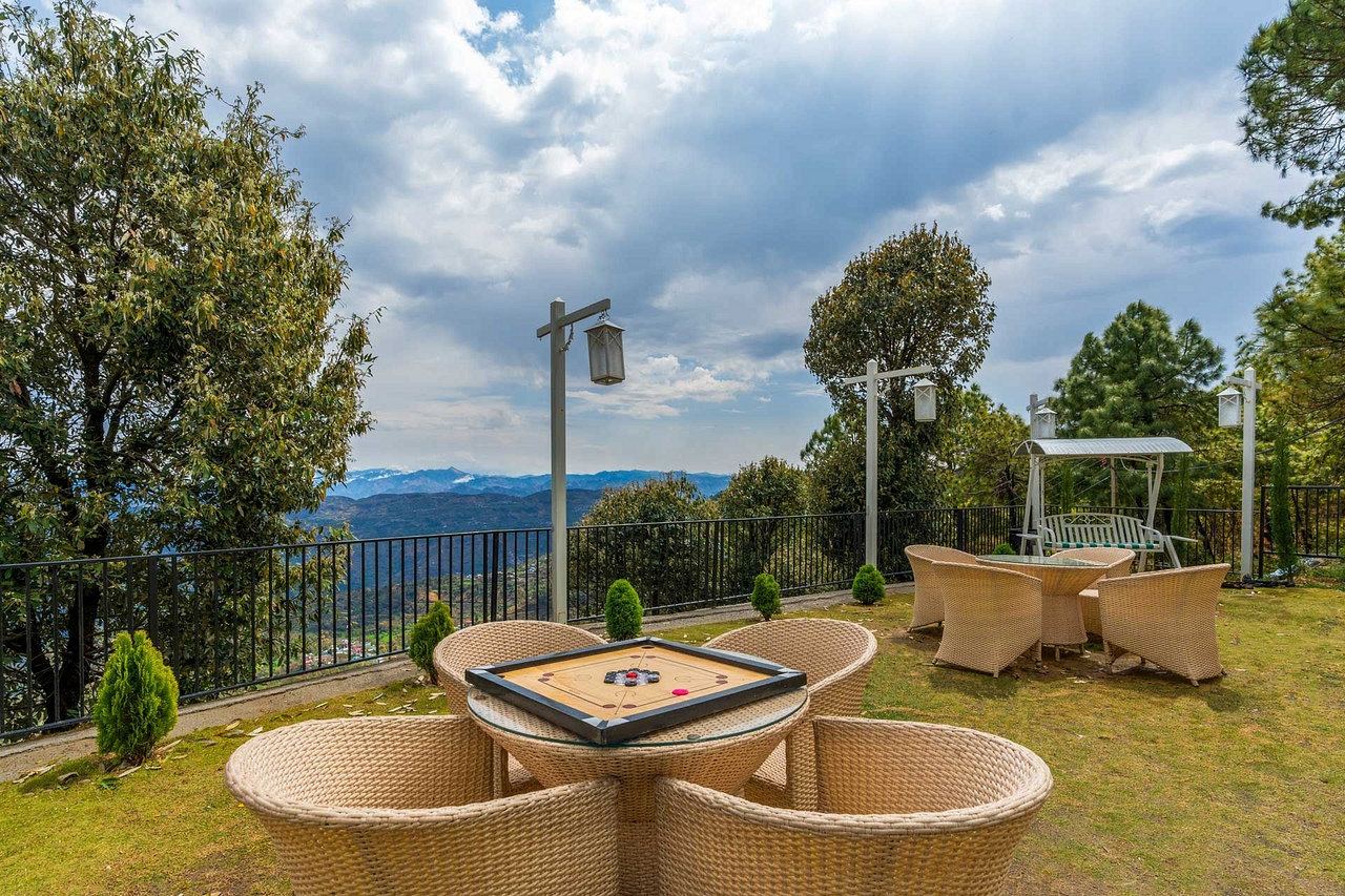 Cane chairs and a round table on the lawn, with the mountains beyond